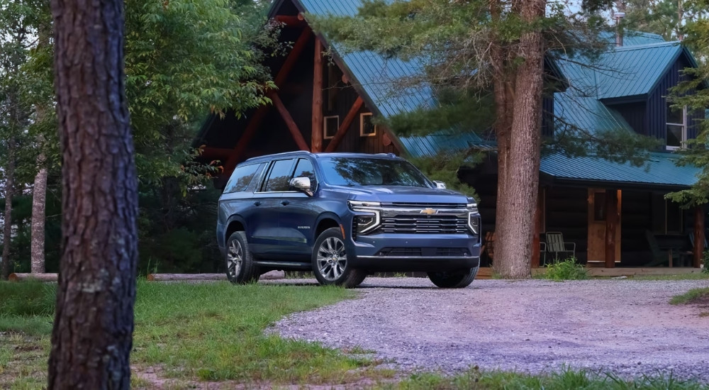 Blue 2025 Chevy Suburban parked near a cabin