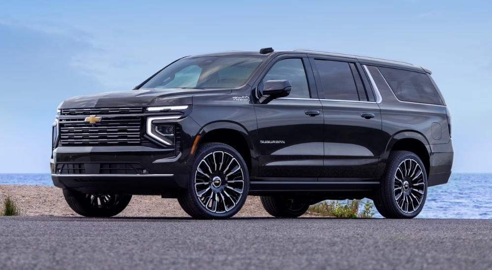 Black 2025 Chevy Suburban High Country parked near a lake