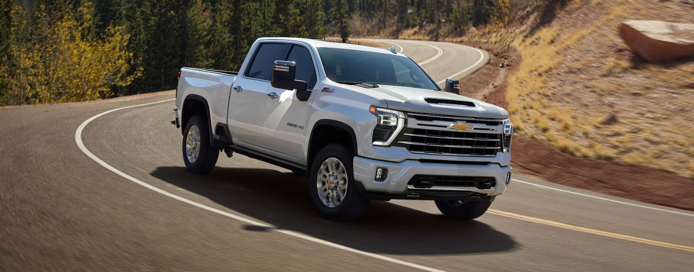 White 2026 Chevy Silverado 2500 HD for sale driving on a winding road