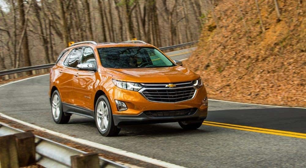 An orange 2019 Chevy Equinox is shown driving on a highway after visiting a used car dealer.