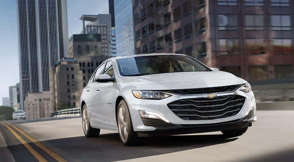 A white 2022 Chevy Malibu is shown driving after visiting a used car dealer near Bessemer.