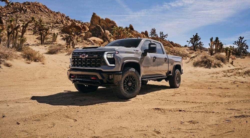 A gray 2024 Chevy Silverado 1500 HD ZR2 is shown parked on sand.