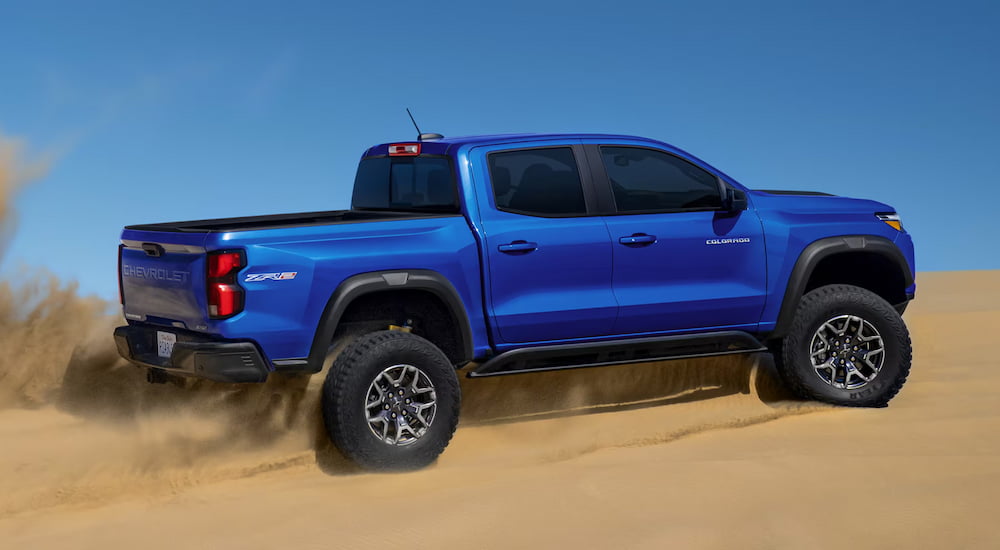 Rear of a blue 2026 Chevy Colorado ZR2 driving off-road.