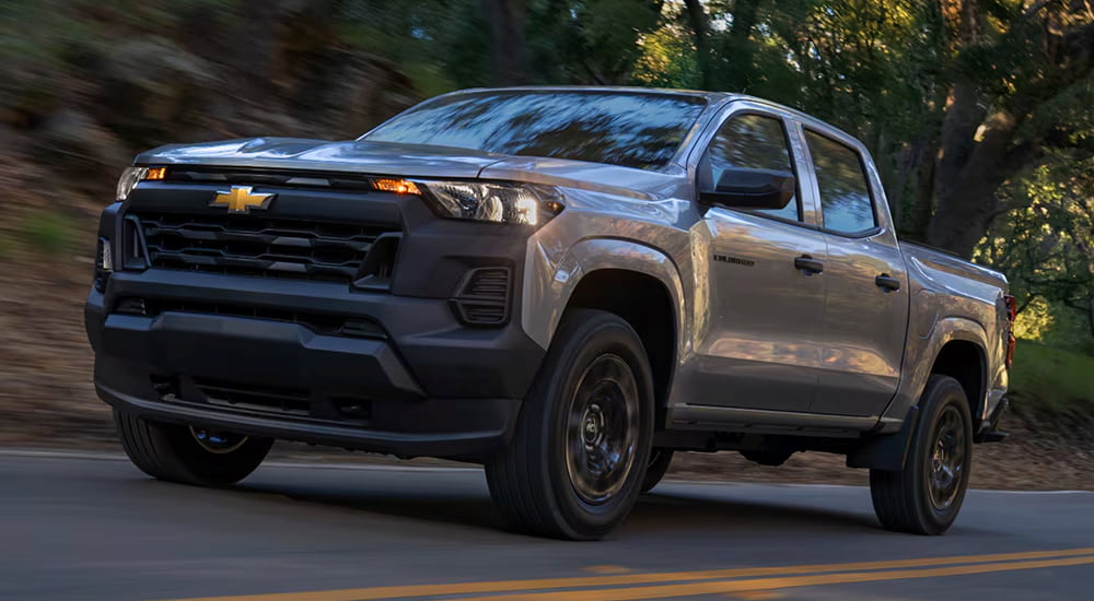 Grey 2026 Chevy Colorado driving down a road.