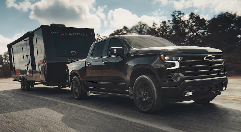 Black 2026 Chevy Silverado 1500 High Country towing a camper van.