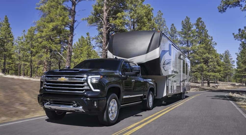 A black 2026 Chevy Silverado 3500 towing a trailer.