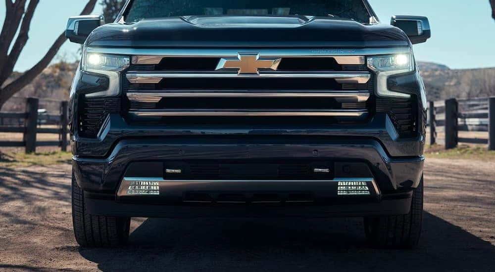A black 2024 Chevy Silverado 1500 High Country is parked on a farm.