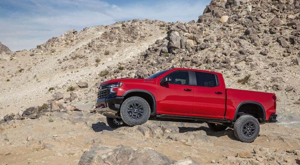 A red 2022 Chevy Silverado 1500 ZR2 is shown from the side while off-road after leaving a dealer that has a Chevy Silverado 1500 for sale.
