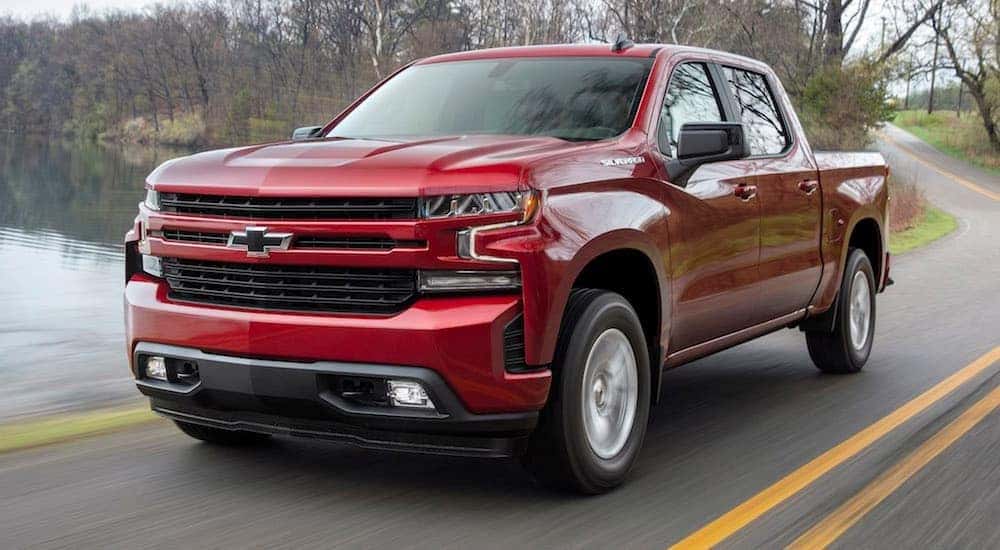 A red 2019 Chevy Silverado 1500 for sale near Bessemer driving past water.