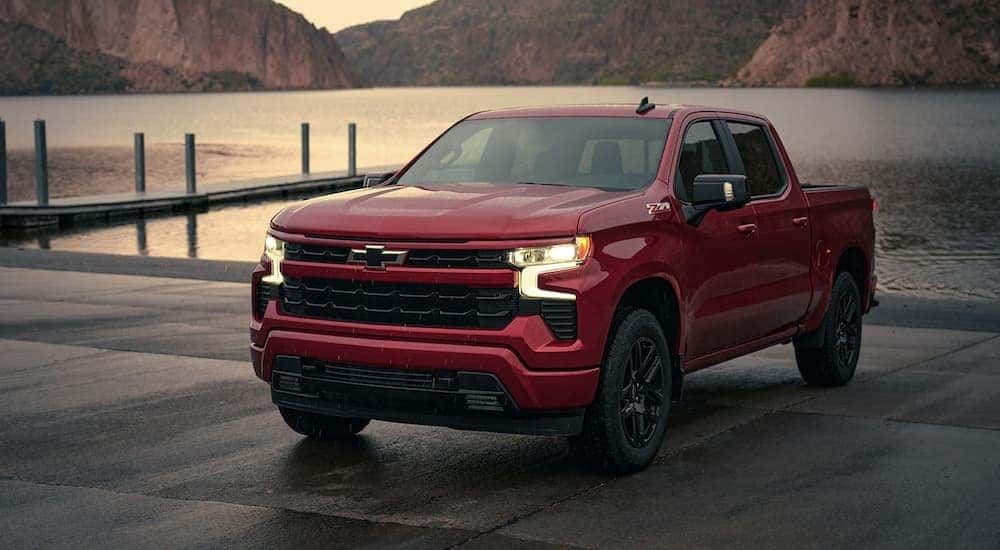 A red 2023 Chevy Silverado 1500 Z71 is shown parked in front of a lake.