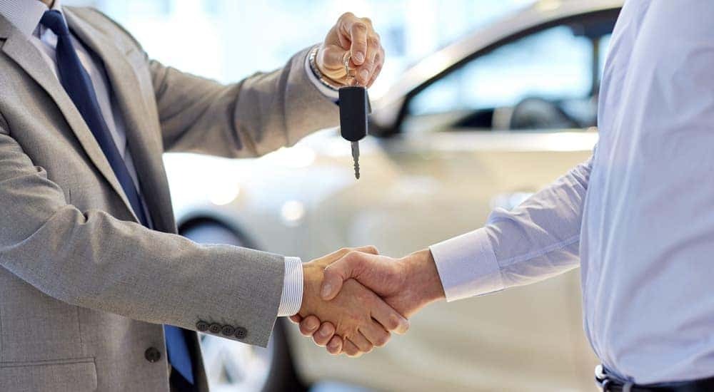 A car salesman is shown handing car keys to customer.