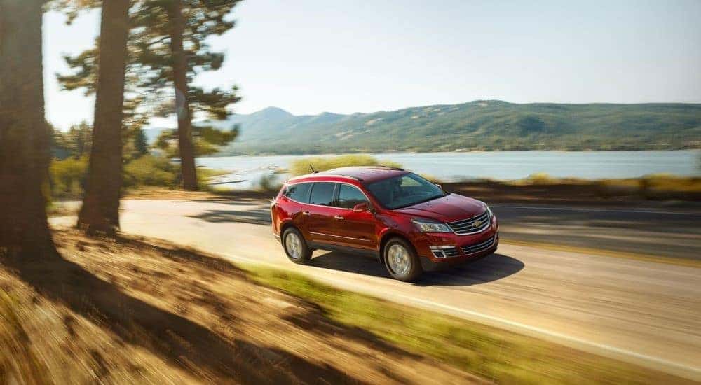 A red 2017 Chevy Traverse is shown passing a lake on the way to 'sell my car'.