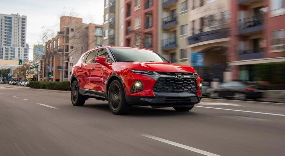 A red 2019 Chevy Blazer RS is shown driving on a city street after looking at used Chevy SUVs for sale.