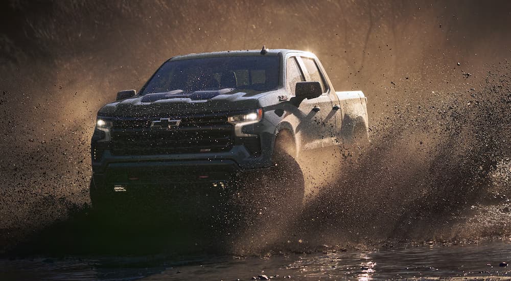 A blue 2026 Chevy Silverado 1500 off-roading in mud