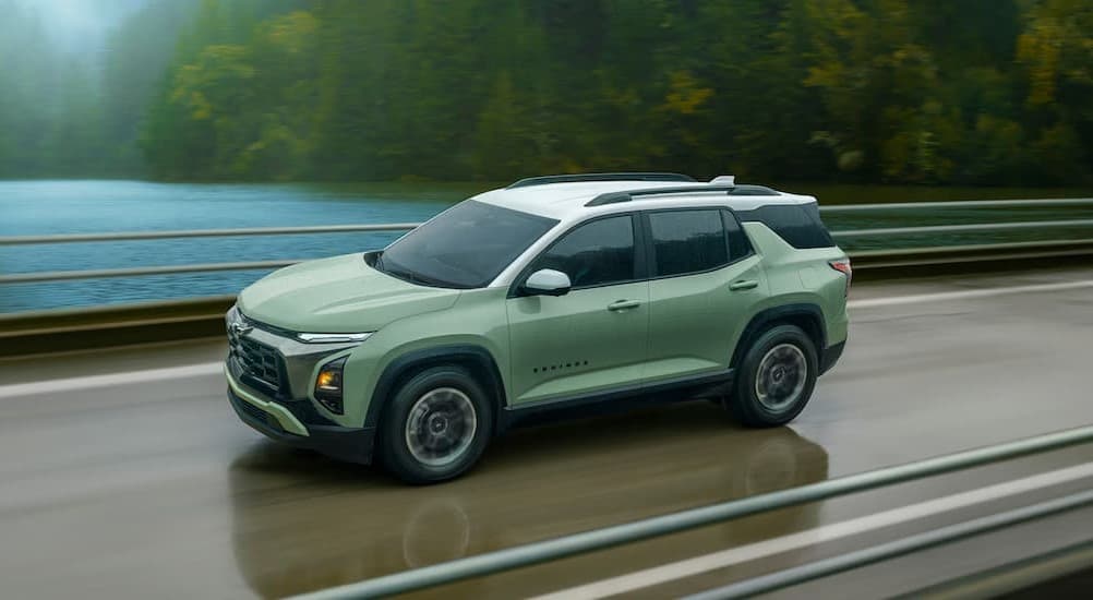 A green 2026 Chevy Equinox ACTIV driving on a bridge.