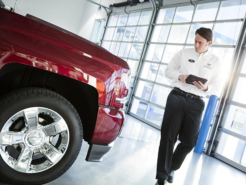 A service professional using a tablet while walking beside a red truck
