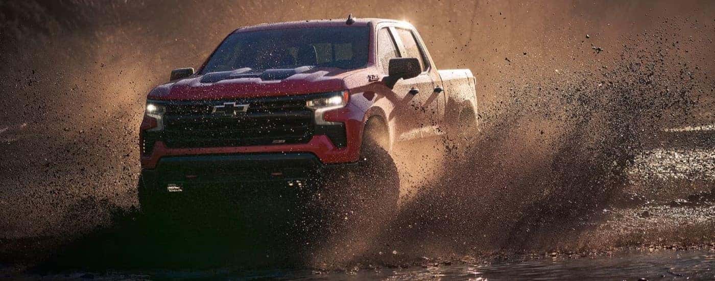 A red 2023 Chevy Silverado 1500 Z71 Trail Boss is shown kicking up mud.