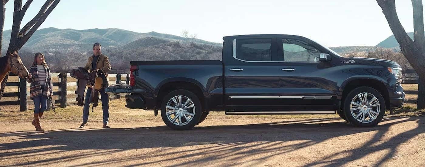A black 2024 Chevy Silverado 1500 High Country is shown parked on a ranch.
