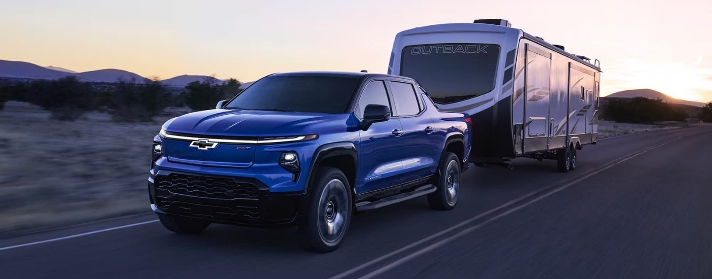 Blue 2024 Chevy Silverado EV RST towing a large camper