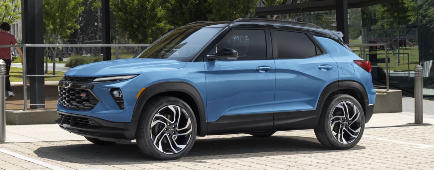 Blue 2026 Chevy Trailblazer RS parked in front of a glass building.