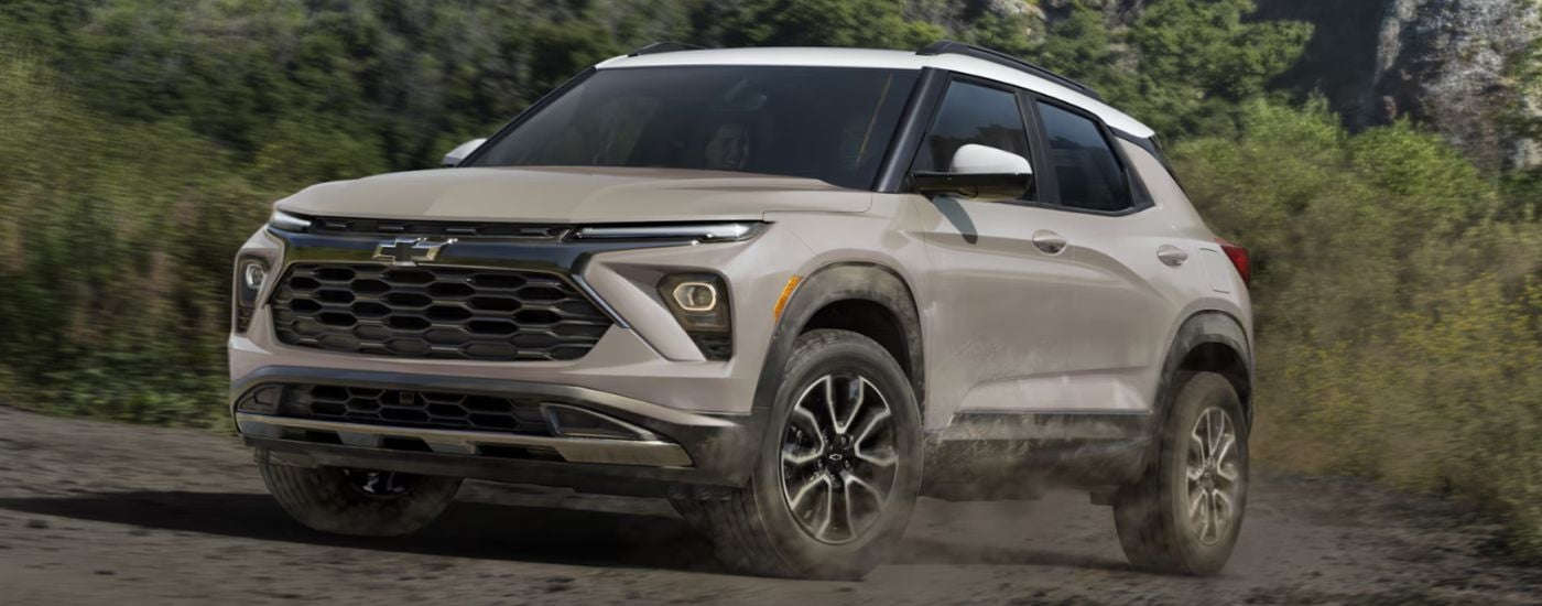 Tan 2026 Chevy Trailblazer driving off-road in the woods.
