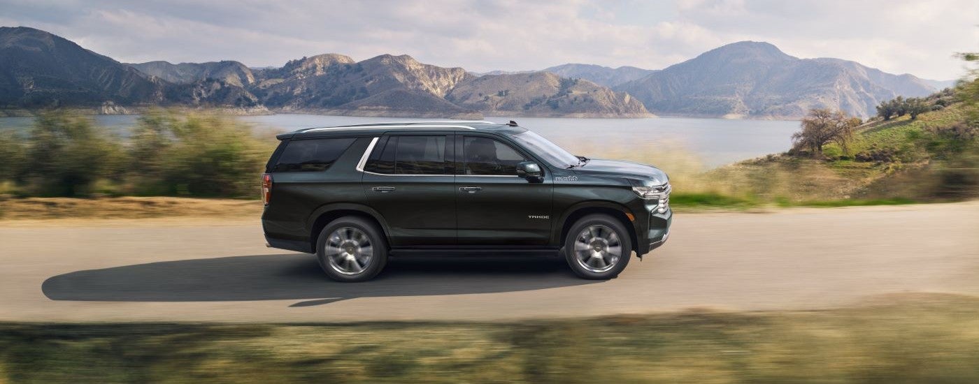 A black 2022 Chevy Tahoe High Country driving by a lake.
