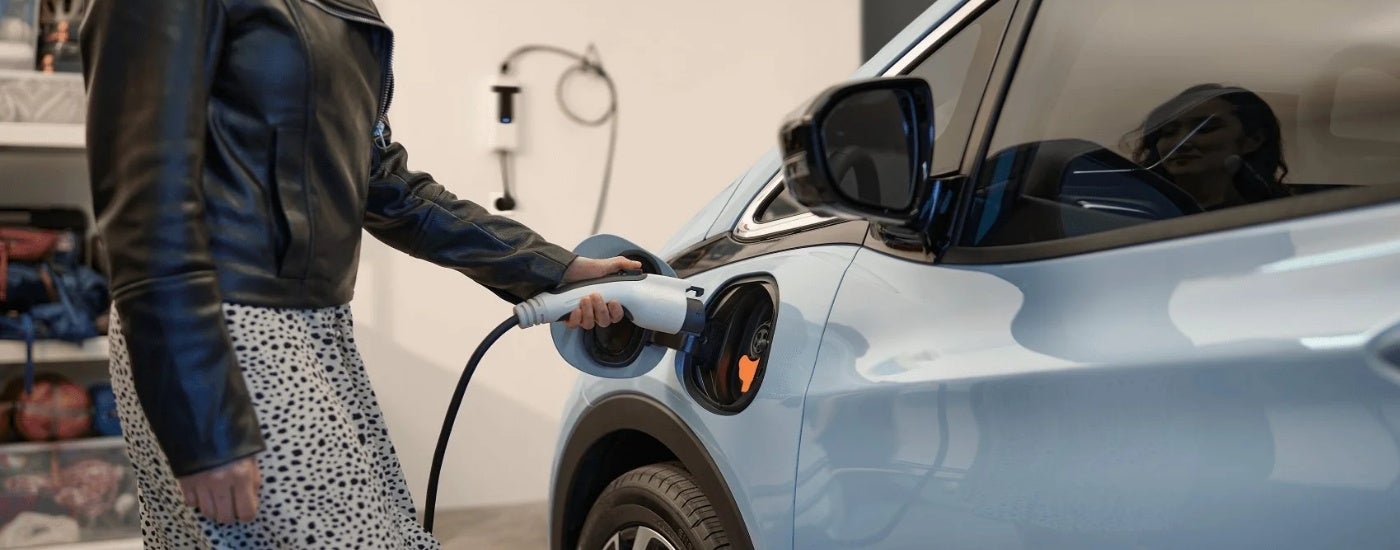 Blue 2023 Chevy Bolt EV is shown being charged in a garage