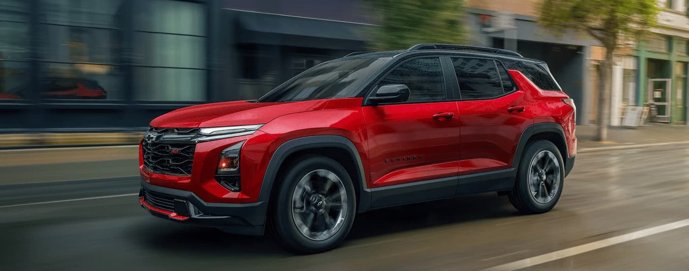A red 2025 Chevy Equinox RS driving in a city.