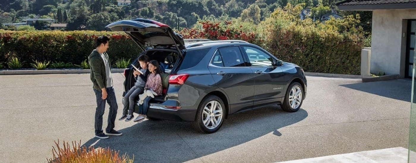 A family is shown next to a grey 2021 Chevy Equinox.