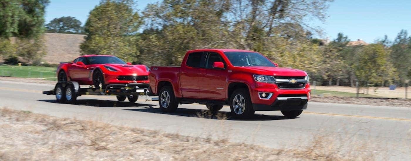 A red 2018 Chevy Colorado is shown towing a red Corvette on a trailer.
