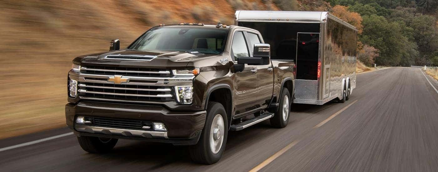 A black 2021 Chevy Silverado 2500 HD High Country towing a trailer to view trucks for sale near Bessemer.