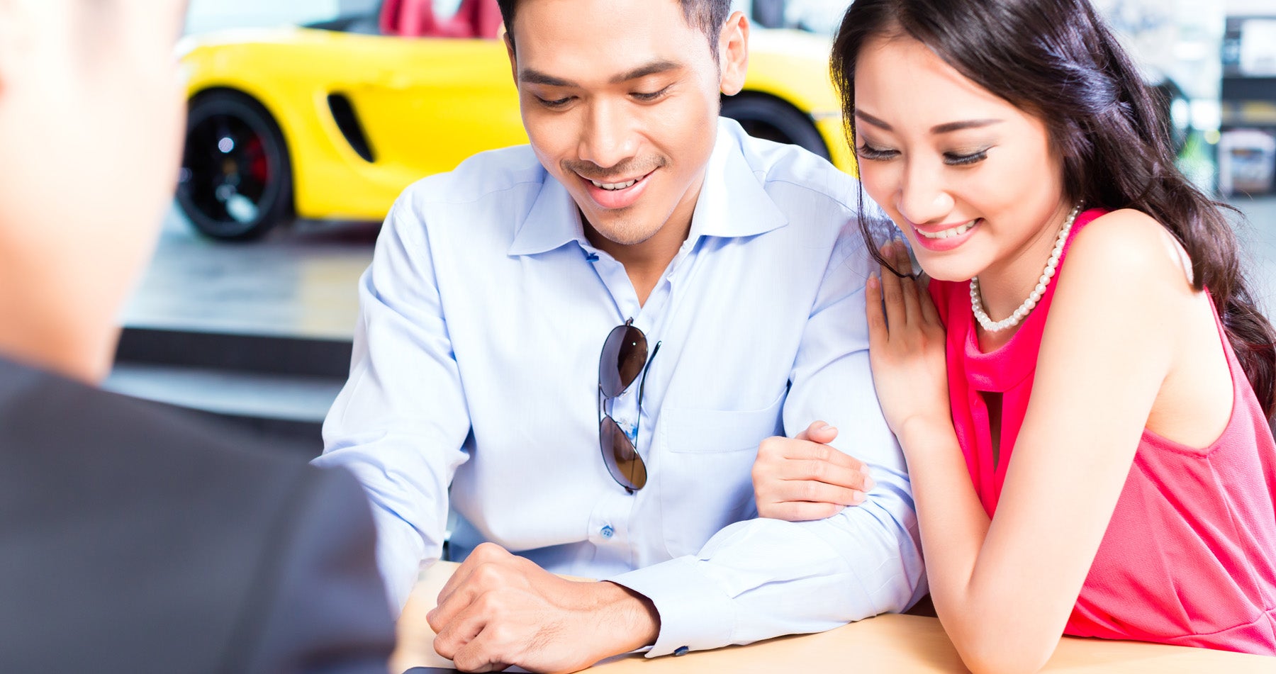 A smiling couple talks with a salesperson in a car dealership
